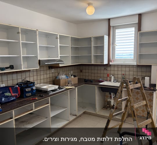 מטבח בתהליך שיפוץ עם ארונות פתוחים וסולם